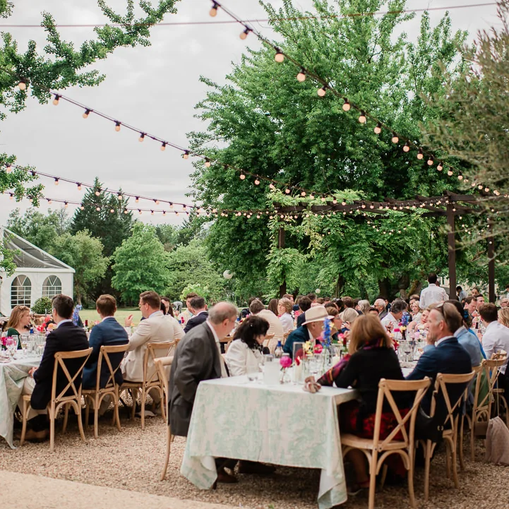Dinner outside under festoon lights, in front of the reception hall