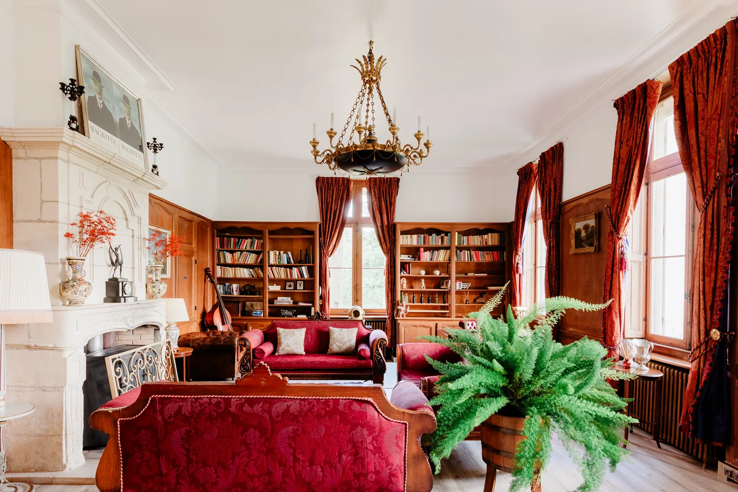 The library, its fireplace and its raspberry sofas