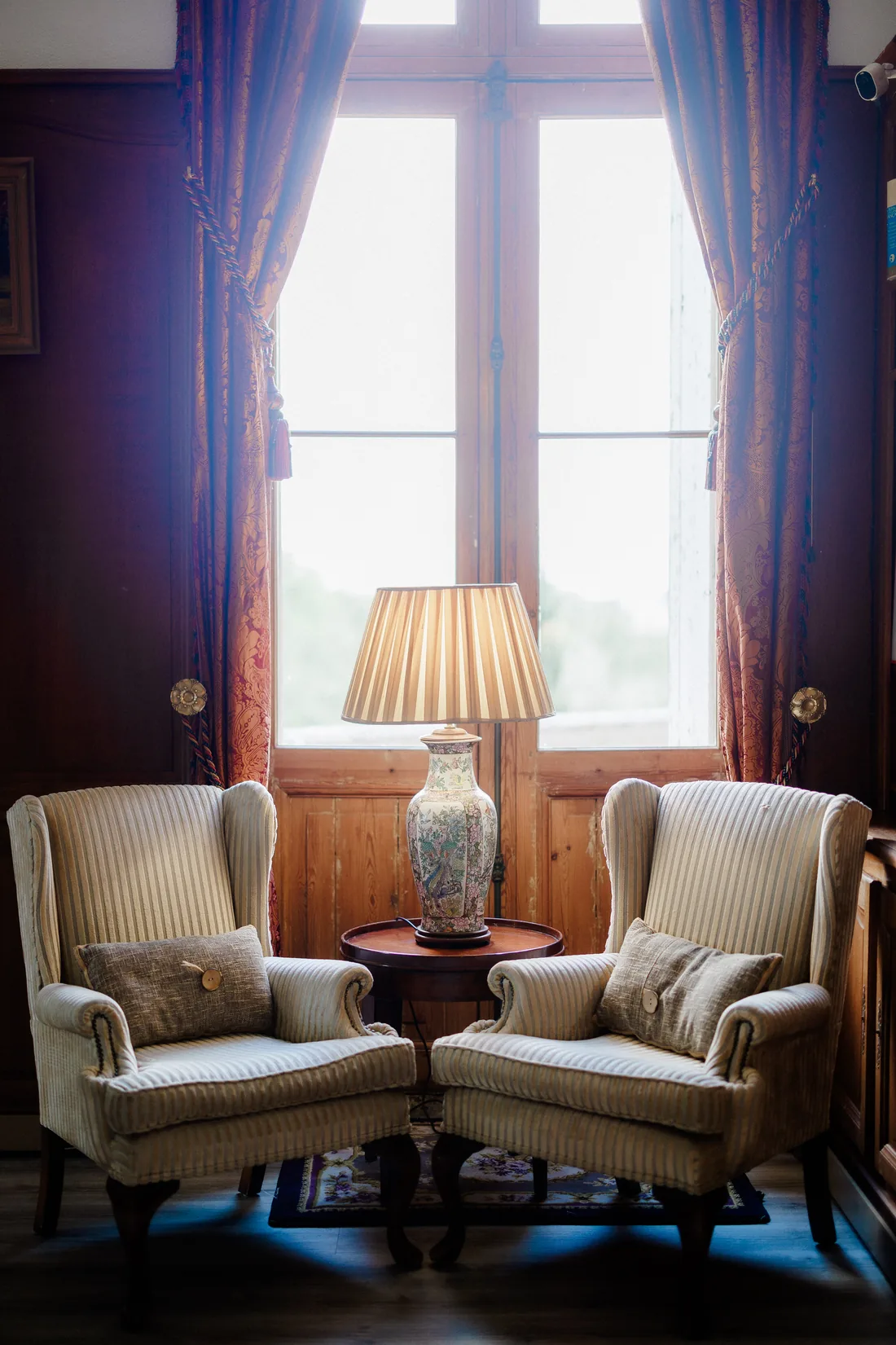 Two armchairs and their lamp by the window