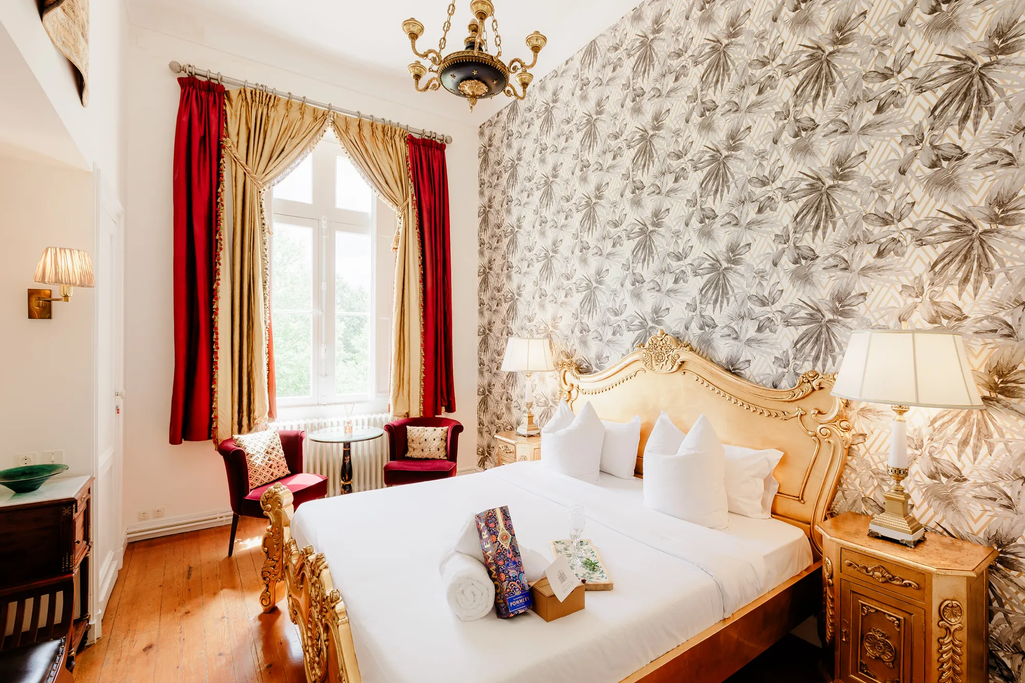 A bedroom with a gilded bed and floral wallpaper