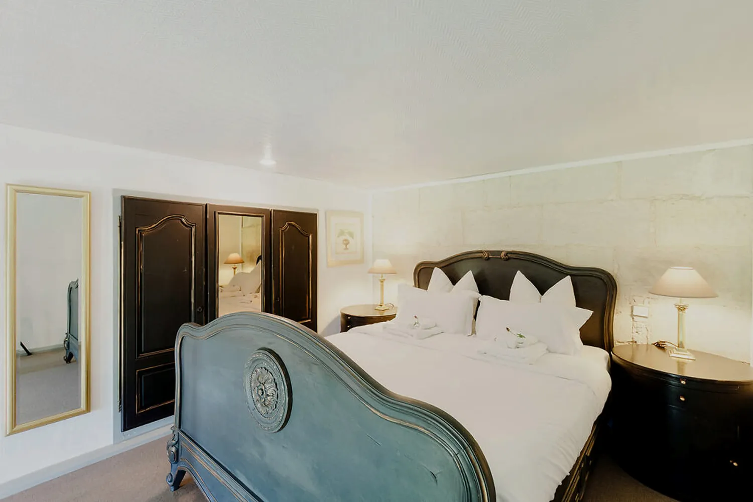 A bedroom with a blue upholstered bed and dark wallpaper