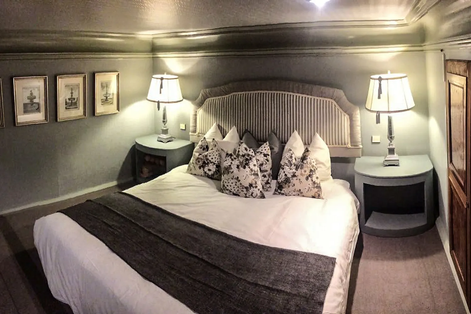A grey bedroom and its wall of framed pictures
