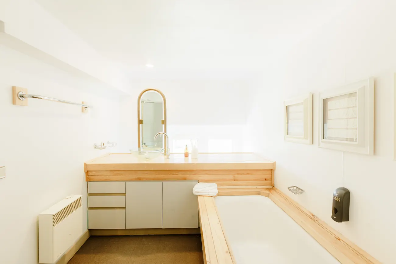 A bathroom with a timber surround and a glass basin