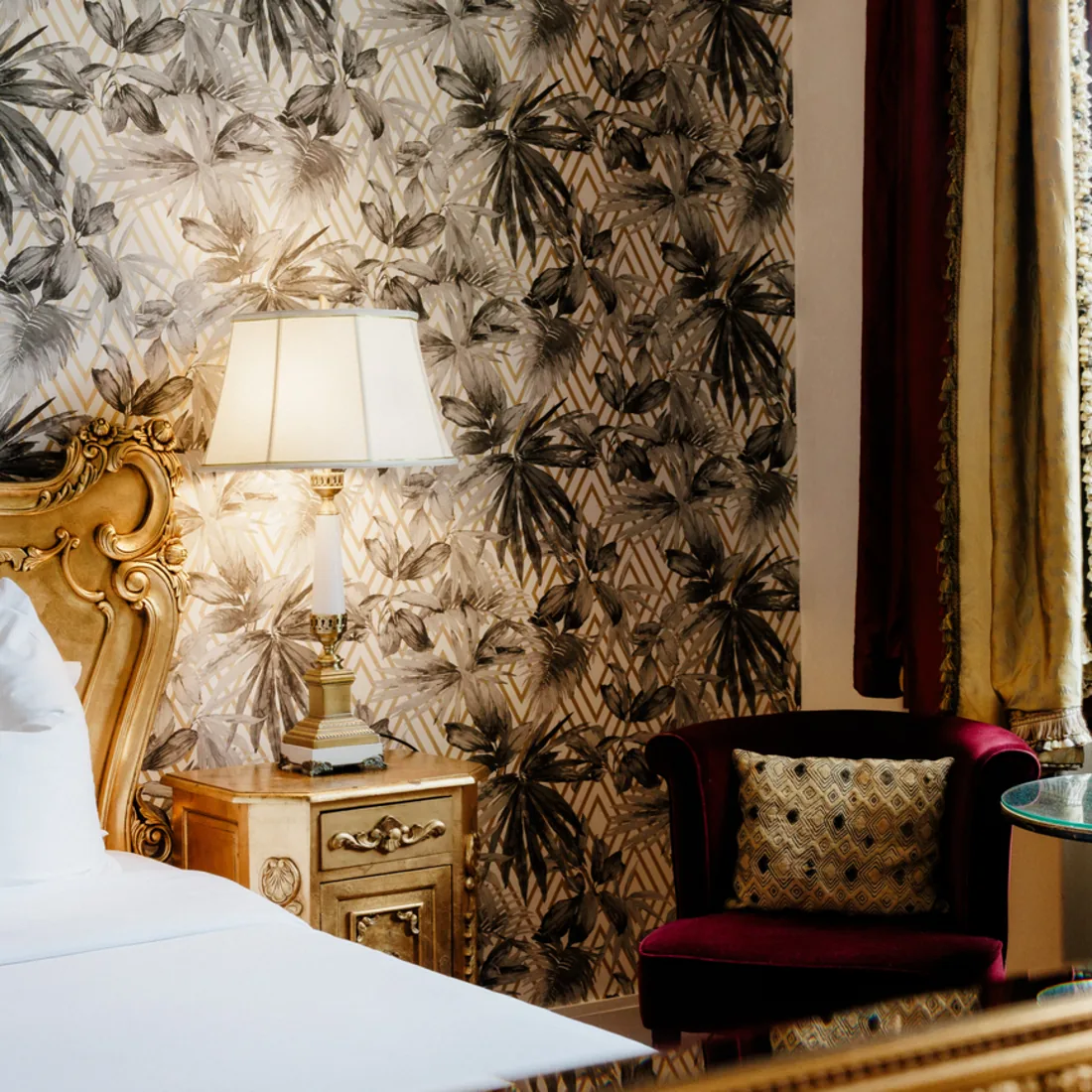 A bedroom dressed in palm-leaf paper, with its gilded bed and burgundy armchair