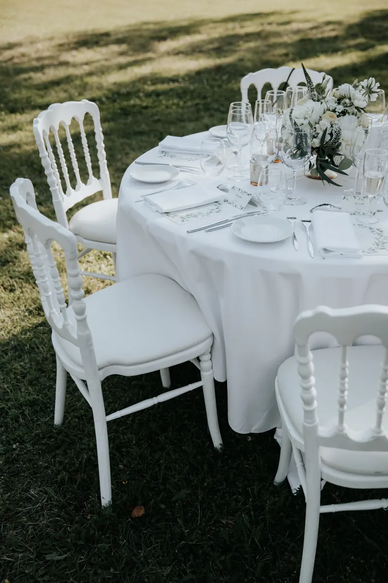 A round table laid in white with Napoleon chairs